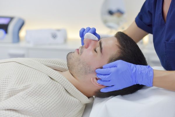 Precio bótox Madrid - Esteticista limpiando el rostro de un hombre antes de aplicar el tratamiento de rejuvenecimiento facial con bótox Madrid
