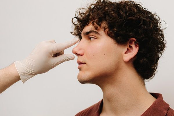 Rinomodelación sin cirugía - Médico estético evaluando la nariz de un hombre para realizar un tratamiento de rinomodelación ácido hialurónico