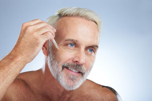 Colágeno y ácido hialurónico - Hombre aplicándose gotas de colágeno y ácido hialurónico Madrid como tratamiento de rejuvenecimiento facial