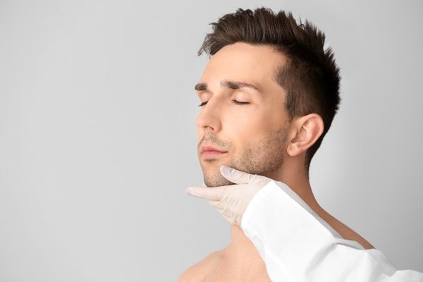 Rellenos faciales - Médico estético evaluando el rostro de un hombre para realizar un tratamiento con relleno facial