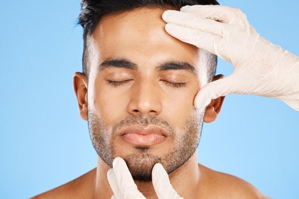 Rellenos faciales - Cirujano estético evaluando los resultados del tratamiento con ácido hialurónico Madrid en el rostro de un paciente masculino