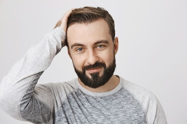 Injerto capilar definitivo - Hombre feliz tocando su cabello abundante luego de un trasplante capilar exitoso