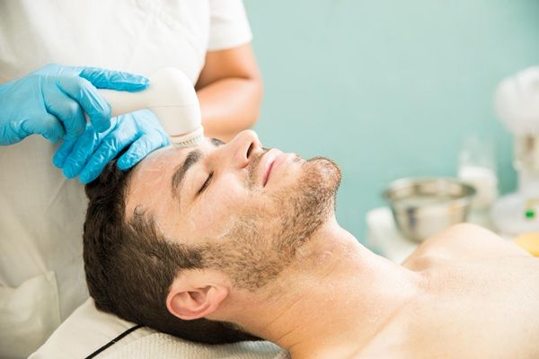 Revitalización facial Madrid - Esteticista realizando un tratamiento de revitalización facial con ácido hialurónico Madrid a un hombre