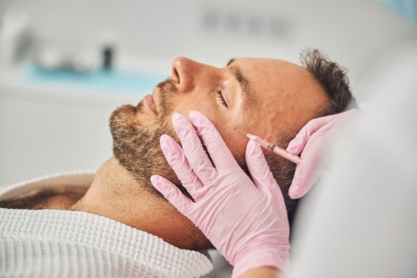 Revitalización facial Madrid - Médico estético aplicando un tratamiento de rejuvenecimiento facial a un hombre en la mejor clínica ácido hialurónico Madrid