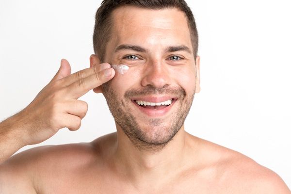 Hombre aplicándose una crema con ácido hialurónico Madrid para rejuvenecer la piel del rostro