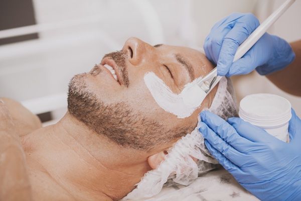 Peeling químico - Médico estético realizando un tratamiento de rejuvenecimiento facial con peeling químico en el rostro de un paciente