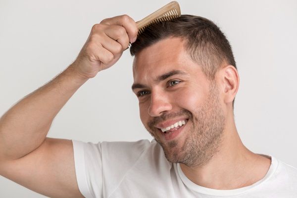 Injerto capilar Madrid - Hombre feliz peinando su cabello luego de un tratamiento de trasplante capilar en la mejor clínica injerto capilar Madrid