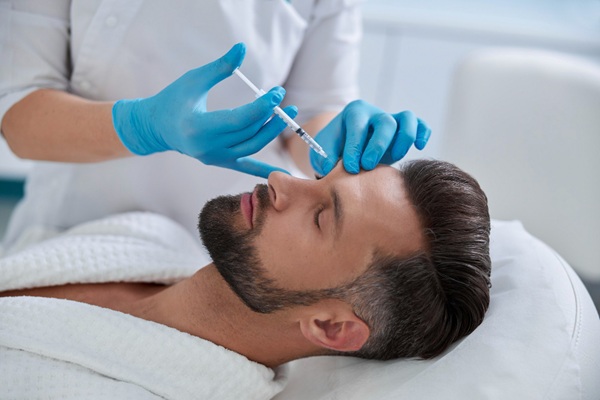 Ácido hialurónico Madrid - Esteticista aplicando un tratamiento de rejuvenecimiento facial a un hombre en una de las mejores clínicas estéticas Madrid