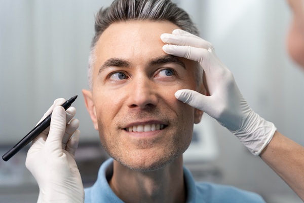 Esteticista realizando el diseño del tratamiento facial para eliminar las ojeras en el rostro de un hombre