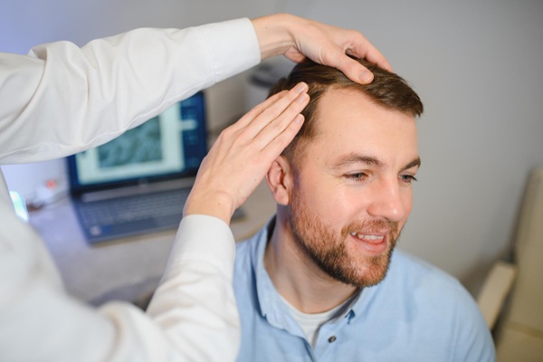 Mejor clínica injerto capilar Madrid - Médico tricólogo evaluando el cuero cabelludo de un hombre con alopecia para determinar el implante capilar precio