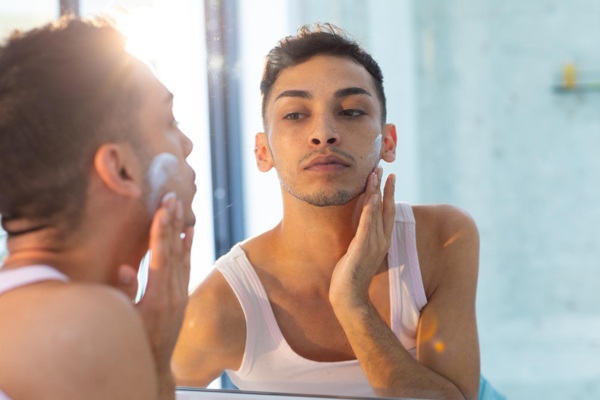 Piel masculina - Hombre frente al espejo aplicándose un skin care como parte de la rutina de rejuvenecimiento facial