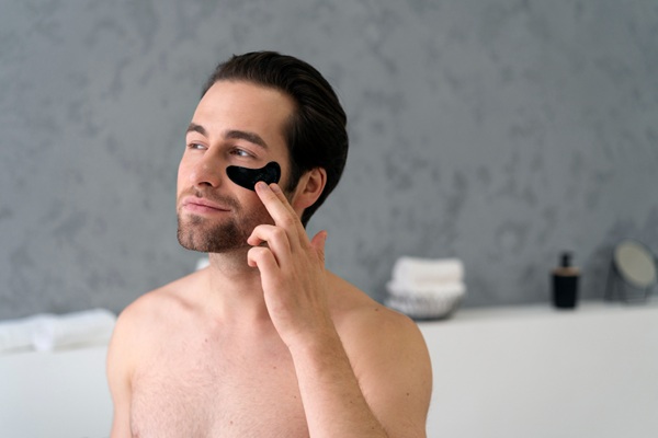 Hombre realizándose un tratamiento facial con carbón activado para exfoliar el rostro