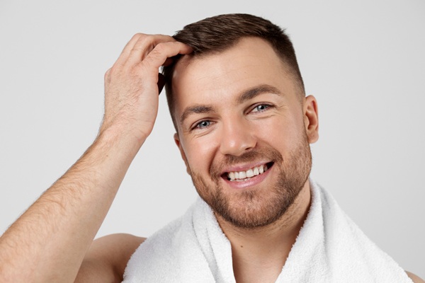 Tratamiento PRP - Hombre feliz tocando su cabello abundante gracias al tratamiento de plasma rico en plaquetas realizado en la mejor clínica injerto capilar Madrid